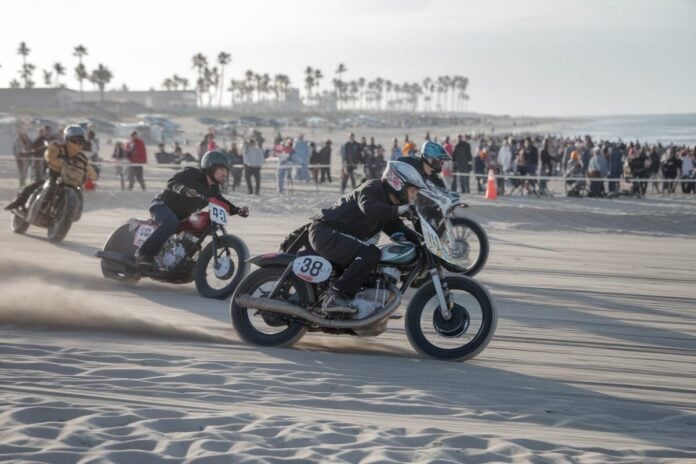 Course de motos sur la plage Course de motos sur le sable avec spectateurs en arrière-plan